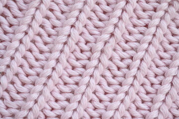 cool pink texture of knitted woolen fabric as a background, pink smooth symmetrical lines of the hand-knitted pattern