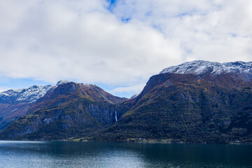 Autumn landscape in Lustrafjorden, South Norway, featuring clear water reflections, mountains, and colorful foliage.