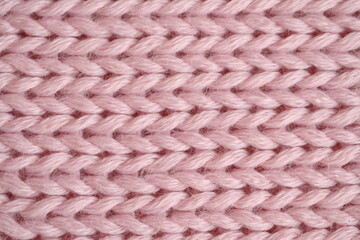 light pink texture of knitted wool fabric as a background, smooth symmetrical lines of hand-knitted needlework pattern	
