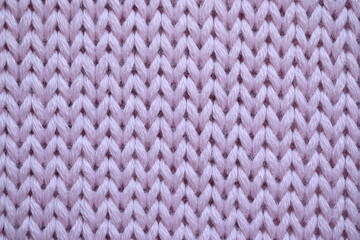cold pink texture of knitted wool fabric as a background, smooth symmetrical lines of hand-knitted needlework pattern