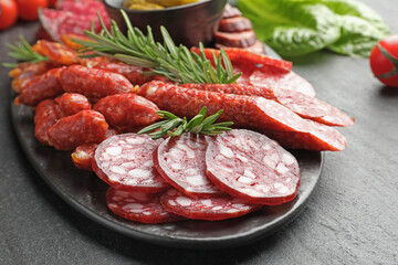Different smoked sausages and rosemary on black table, closeup