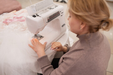 Portrait of seamstress in a wedding salon sews a wedding dress and veil,  handmade, boutique. Small local business, self-employment.