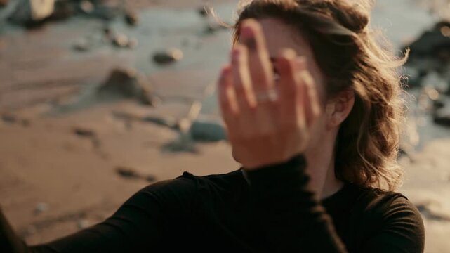 A dancer elegantly poses on a beach during sunset, capturing a moment of peacefulness and grace. The ocean waves and soft lighting complement the artistic expression.
