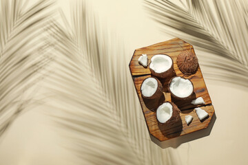 Fresh coconuts and shadow cast by tropical palm on beige background, top view. Space for text