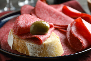 Sandwich with delicious sausage and olive served on table, closeup