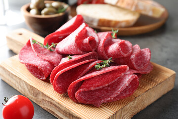 Slices of delicious sausage with thyme served on grey table, closeup