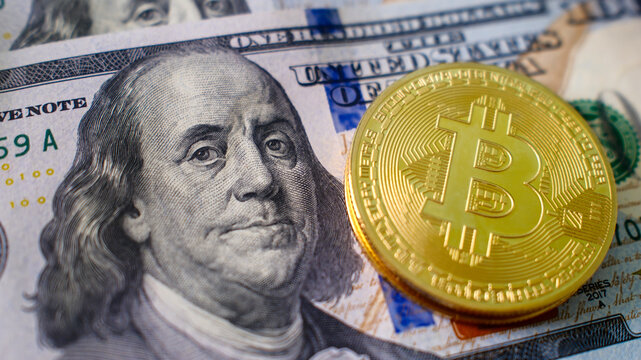 Bitcoin coin placed on US hundred dollar bill, cryptocurrency and traditional fiat currency concept