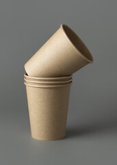 Disposable beige kraft paper cups on a gray closeup, mockup. No plastic and sustainable lifestyle