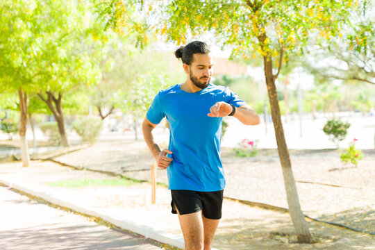 Young male runner checking smartwatch while running in park