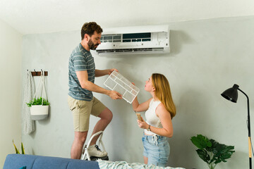 Caucasian couple cleaning air conditioner filter at home during summer