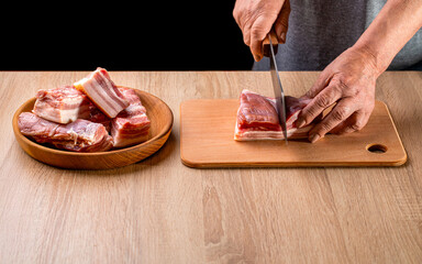 Man cutting raw pork meat on wooden table. Butcher hands close up. Cutting meats. Butcher cuts the meat raw fresh pork on wooden board. Woman cutting pork lard meat on kitchen