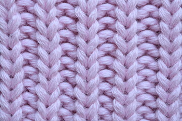 pink texture of knitted wool fabric as a background, purple smooth symmetrical lines of hand-knitted needlework pattern	
