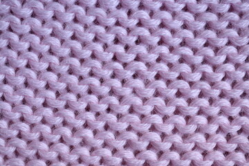 pink texture of knitted wool fabric as a background, purple smooth symmetrical lines of hand-knitted needlework pattern	
