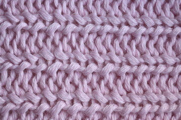 pink texture of knitted wool fabric as a background, purple smooth symmetrical lines of hand-knitted needlework pattern	
