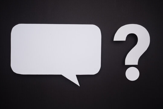 White paper cutout of a speech bubble and a question mark on black background.