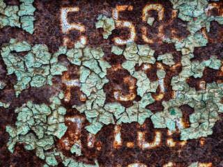 Close-up of rust and peeling paint on aged metal with numbers.