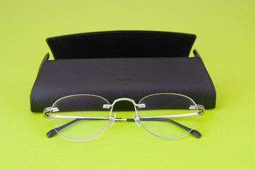 Modern eyeglasses with case close up on green background