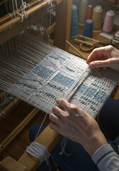 Artisans weaving fabric on a loom with colorful threads  