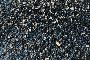 Road repair patching compound closeup. Driveway asphalt pothole patch. Compound filled potholes and cracks on an asphalt surface. Bitumen and gravel mix for repair asphalt road