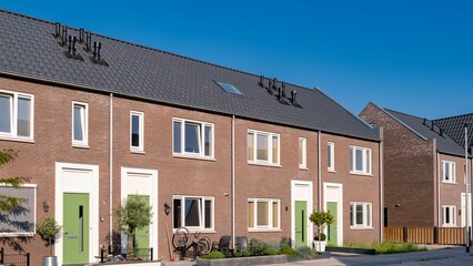 Modern family homes line a picturesque street in a Dutch suburban neighborhood