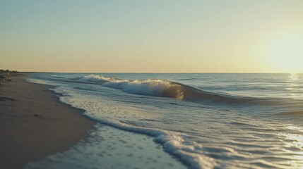 Obraz premium Waves rolling gently onto a sandy beach at sunset or sunrise