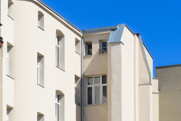 Modern white building with geometric shapes and windows against a clear blue sky