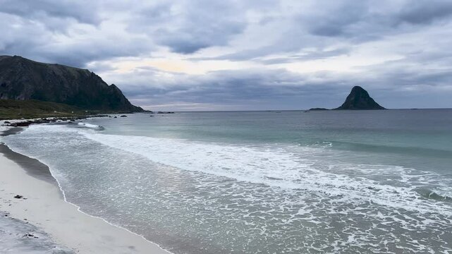 White sand beach with turquoise ocean water and a mountain in Bleik beach, Lofoten islands, Norway