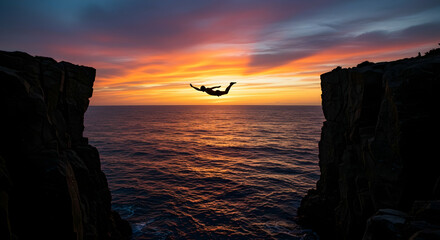 Silhouette of a person cliff jumping into the ocean at sunset achieving a sense of freedom and exhilaration