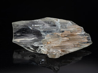 A captivating raw beryl crystal specimen highlighted against a black backdrop, showcasing its...