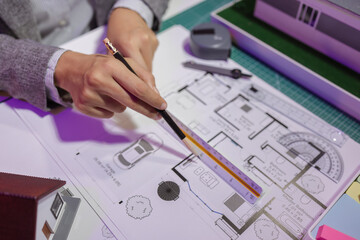 a beautiful female architect is working in her private office because she needs to concentrate on improving the blueprints to be in accordance with the law, engineer, foreman, contractor