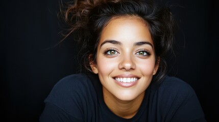 A woman with green eyes and a black shirt. She is smiling. She has a white smile