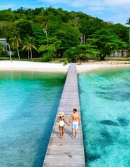 Couples walk hand in hand along a beautiful wooden pier in a tropical paradise by the sea