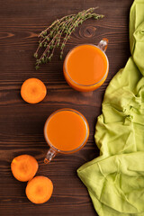 Two glasses with carrot juice, on wooden background and green textile. Diet, healthy eating. top view, close up