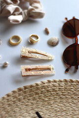 Sunglasses, straw hat, shells and jewelry in neutral colors. Seasonal summer accessories on white background. Selective focus.