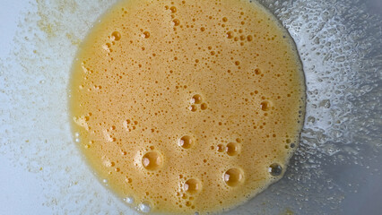 Foamy golden batter in a mixing bowl, essential for baking, Easter treats, festive culinary...