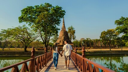 Couple enjoying a serene stroll across the bridge at Wat Sa Si in Sukhothai historical park