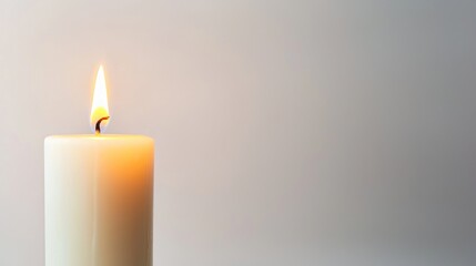 White pillar candle with smooth texture and bright flame on white background.
