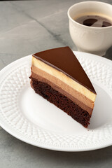 Decadent layered chocolate cake served with a cup of coffee on a gray marble table