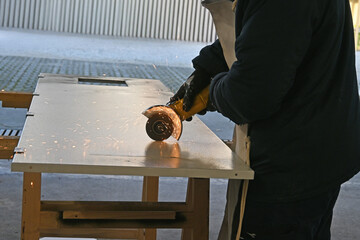 Taglio di lamiera con flessibile a disco, schegge roventi di ferro e scintille gialle arancio