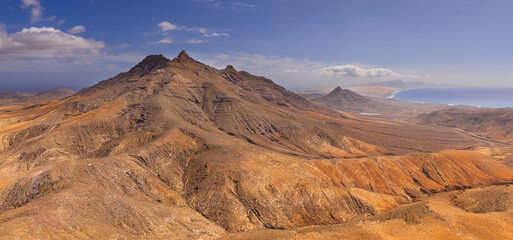 Naklejka premium Dramatic aerial panoramic image of Montana Cardon, the Jandia peninsular and the volcanic mountain landscape of Fuerteventura Canary Islands Spain