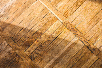 Wooden floor with diagonal patterns and soft sunlit shadows creating a warm ambiance
