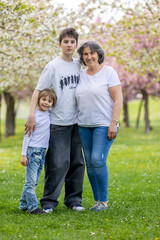 Portrait of cute stylish smiling family, boys and grandmother sitting in the grass in park