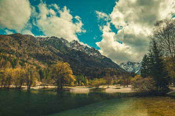 A tranquil scene from Kranjska Gora, Slovenia, featuring a crystal clear turquoise lake in the foreground.