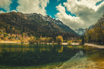 A tranquil scene from Kranjska Gora, Slovenia, featuring a crystal clear turquoise lake in the foreground.