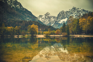 A tranquil scene from Kranjska Gora, Slovenia, featuring a crystal clear turquoise lake in the foreground.