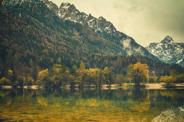 A tranquil scene from Kranjska Gora, Slovenia, featuring a crystal clear turquoise lake in the foreground.