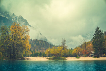 A tranquil scene from Kranjska Gora, Slovenia, featuring a crystal clear turquoise lake in the foreground.