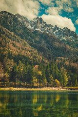 A tranquil scene from Kranjska Gora, Slovenia, featuring a crystal clear turquoise lake in the foreground.