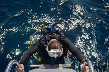 Scuba diver climbing back on boat after diving in the ocean