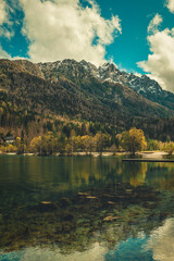 A tranquil scene from Kranjska Gora, Slovenia, featuring a crystal clear turquoise lake in the foreground.